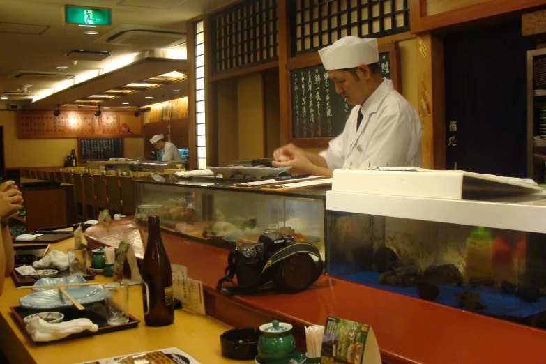 a chef making sushi in a restaurant by his server