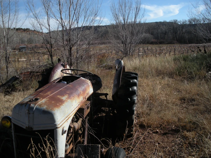 an old rusty tractor is sitting on the side of the road