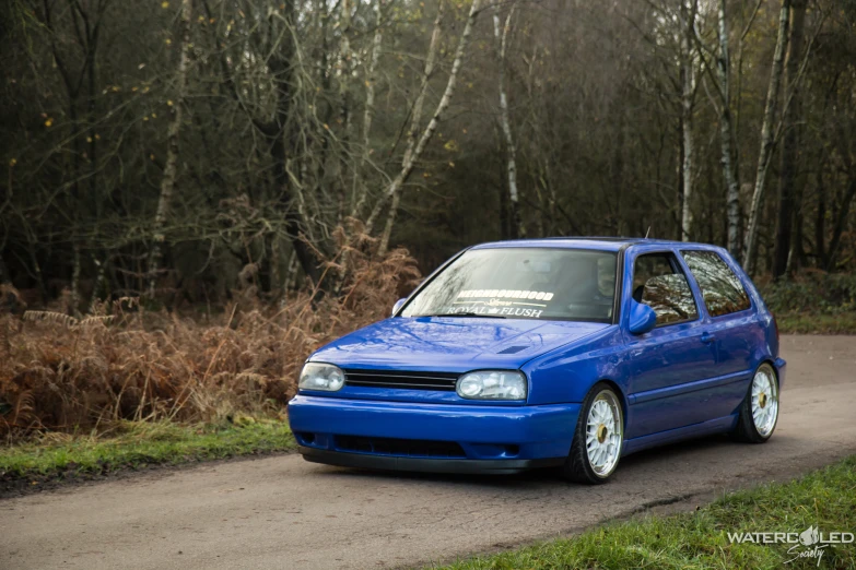 a small blue car is driving down a rural road