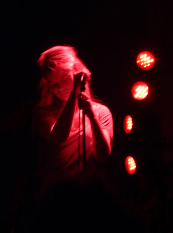 a woman holding a microphone on stage with red lights around her