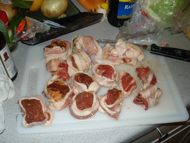 the table is cluttered with raw meats and ingredients