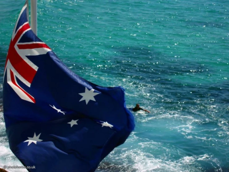 an australian flag flying next to the ocean