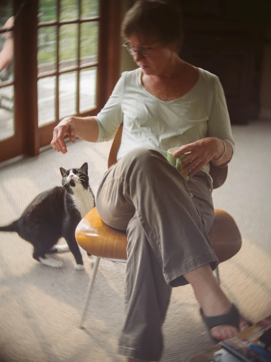 an older woman sitting in a chair petting a cat