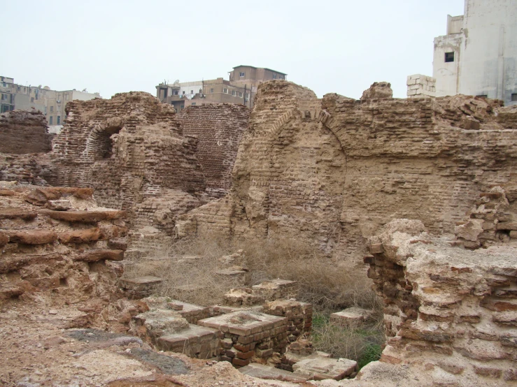 an old city has a crumbling wall and several steps leading up to a fire place