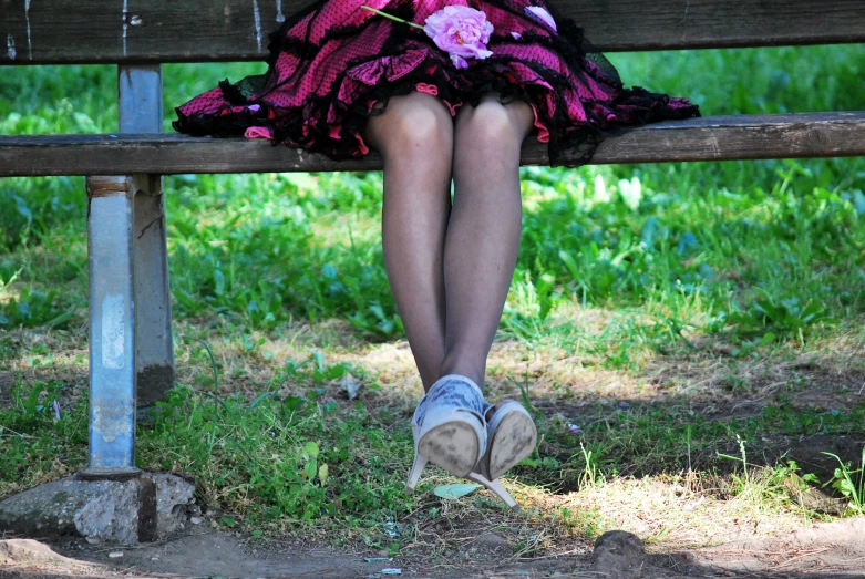 a woman is sitting on a bench and wearing a skirt