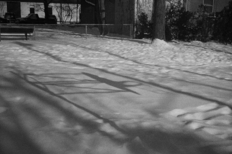 snow covered ground with a bench and buildings