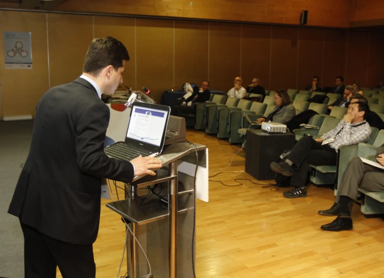 there is a man standing in front of a podium with a laptop computer