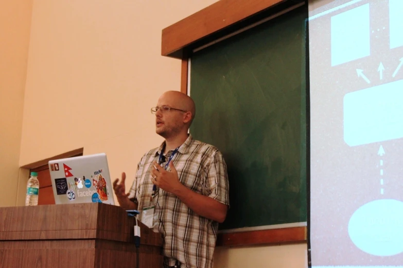 a man standing at a podium with a laptop