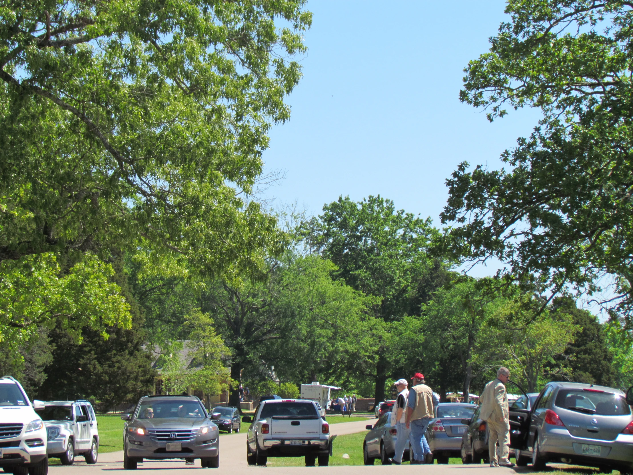 several people walking across the road, many cars and trucks