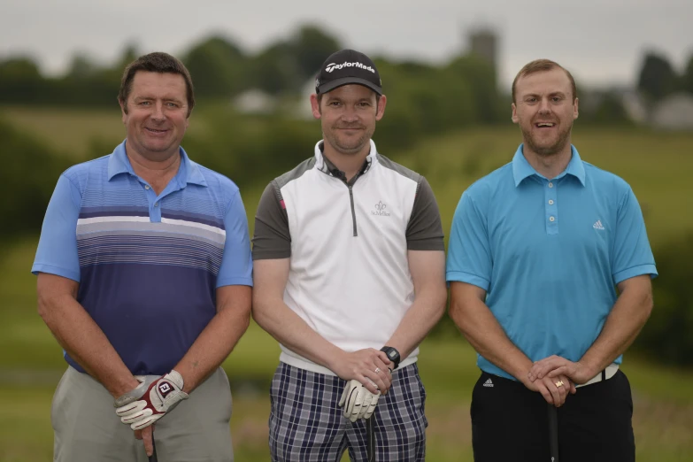 three men pose for the camera with their golf gear