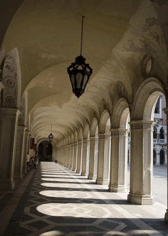 the arches of a building with a lamp hanging above it