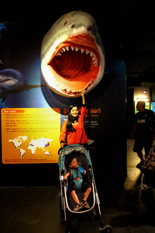 a woman hing her child in a stroller near an image of shark