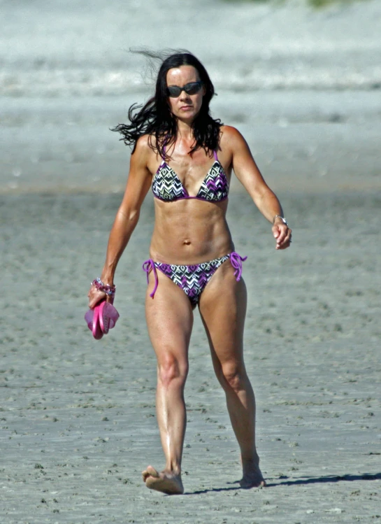 a woman in a bikini walking on the beach