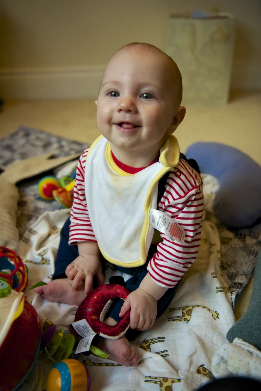 an infant holding a toy on a blanket