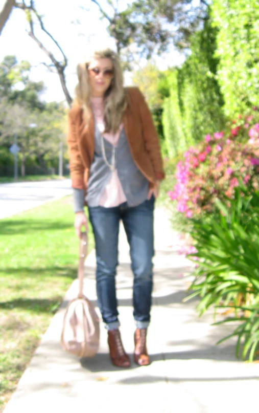 a woman is walking down a sidewalk carrying a pink bag