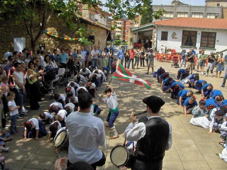 a crowd of people and adults are lined up on the sidewalk