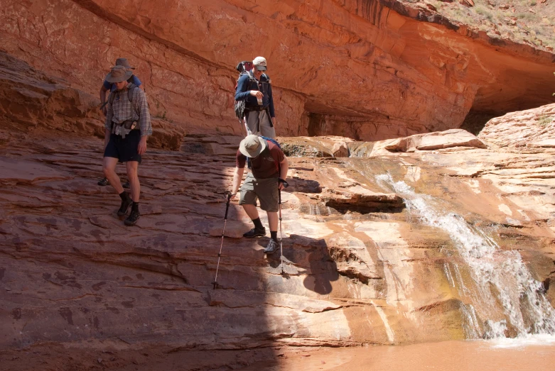 several hikers hiking up the side of a red - rock waterfall