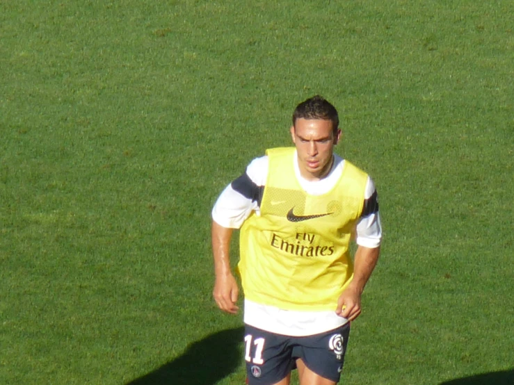 man wearing soccer uniform standing on soccer field with ball