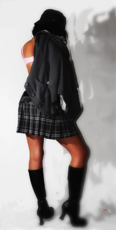 girl wearing short skirt and high boots leaning against the wall