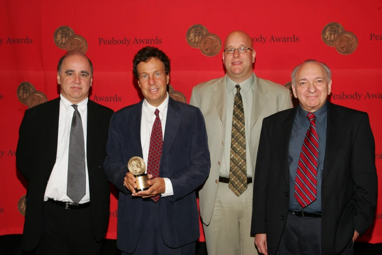 men in suits are holding an award while standing next to each other