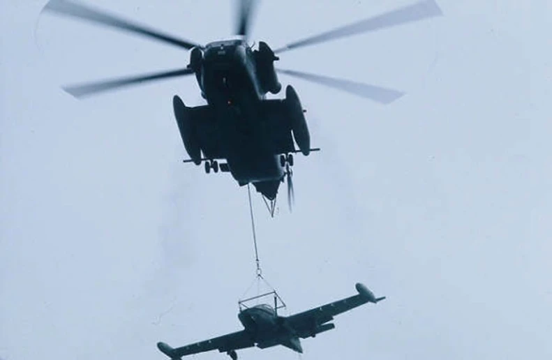 the two army aircraft are being suspended by a helicopter