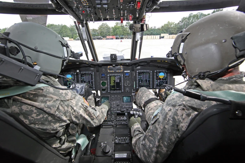 two men in military uniform are sitting inside a helicopter