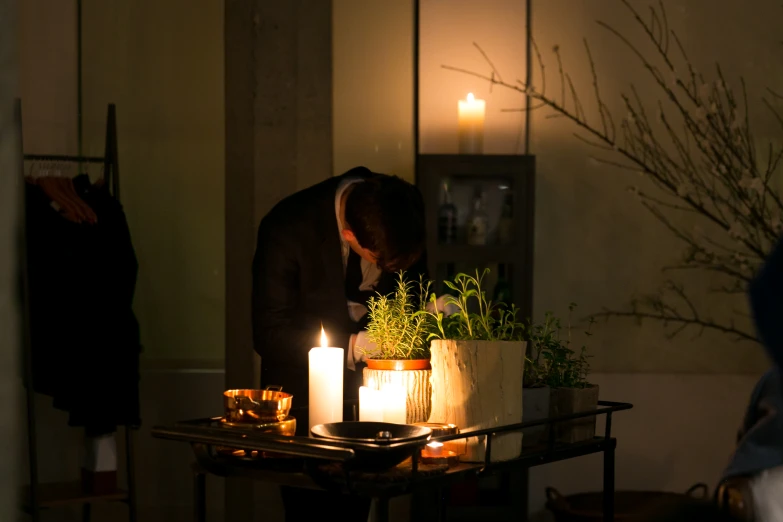 man placing candles in large vases at night time