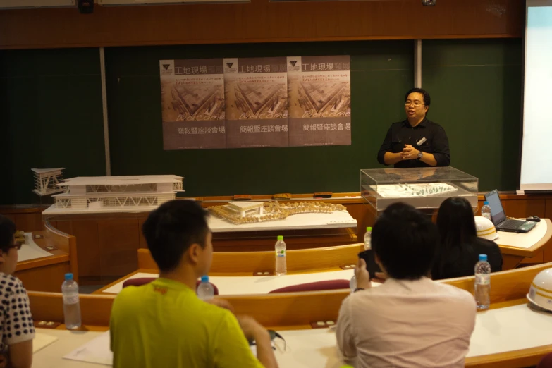 an asian man is at the front of a class of students