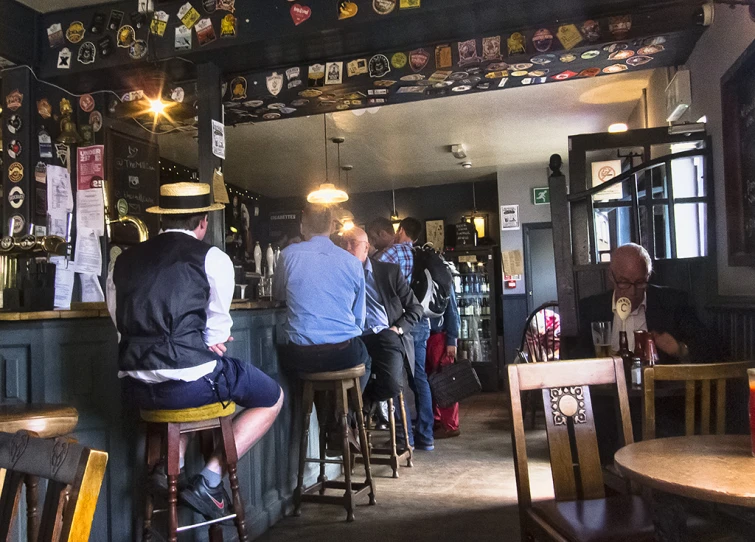 several people stand at a bar in a small pub