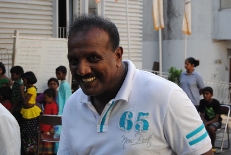 a man smiles while wearing a white shirt