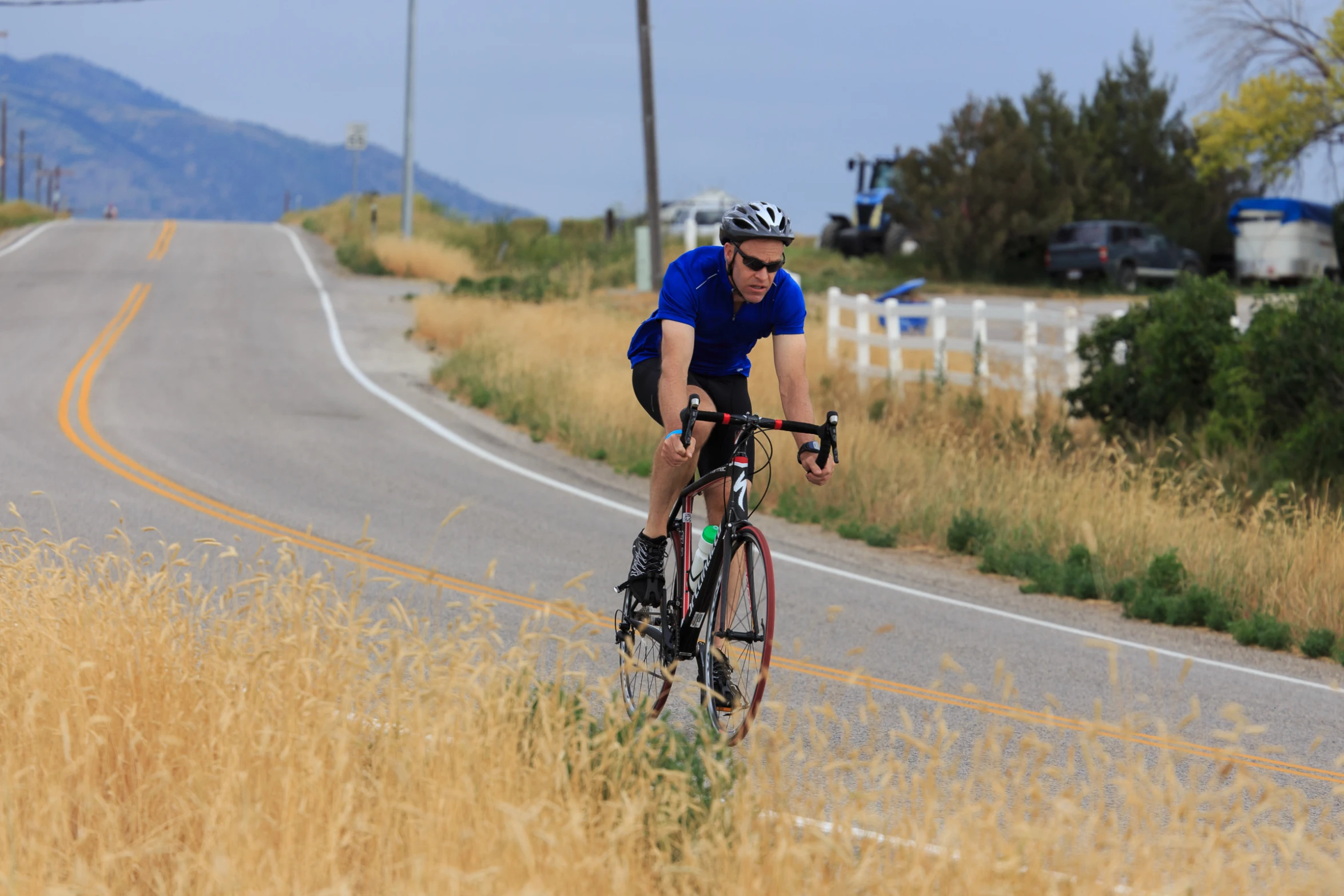 the man in a blue shirt is riding his bike on the road