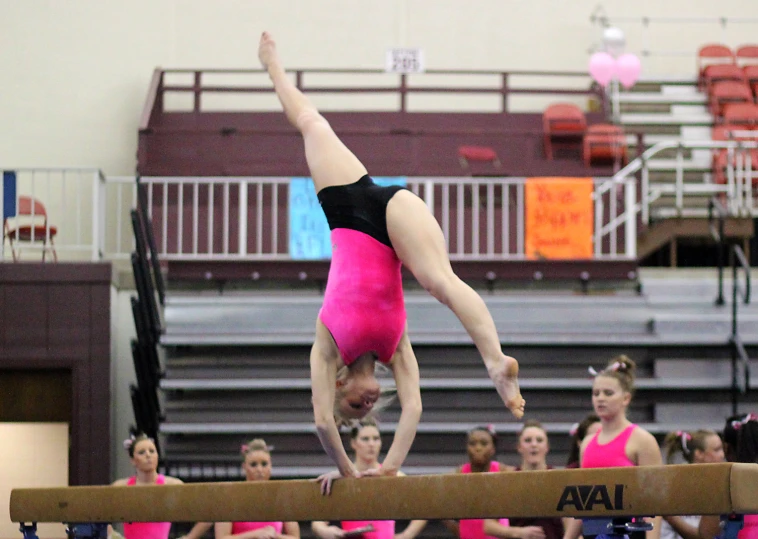 a woman is doing a trick on the beam