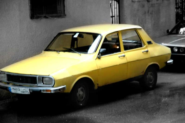 an old and worn yellow car sits on the curb