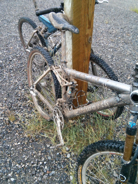 there is a dirty bicycle leaning against the fence