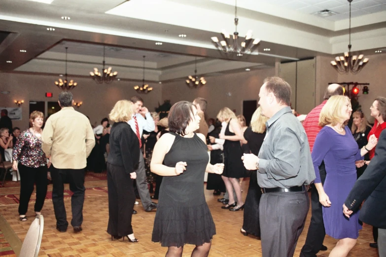 a crowd of people in formal attire dance at an event