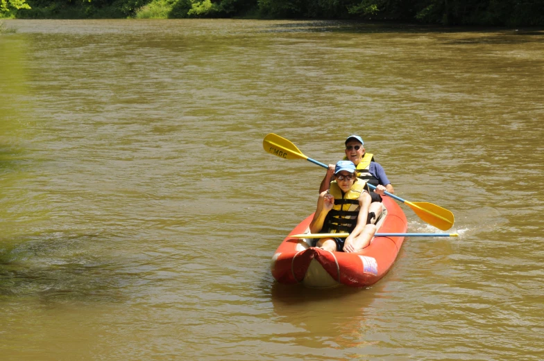 a couple of men riding on the back of a kayak in a river