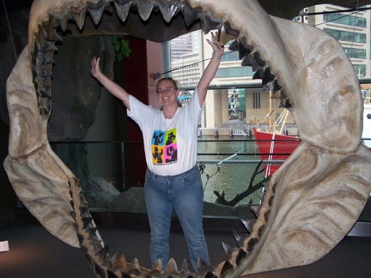 a young man with his hands up inside of a giant model shark