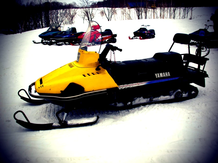 yellow snowmobile and other vehicles parked in the snow