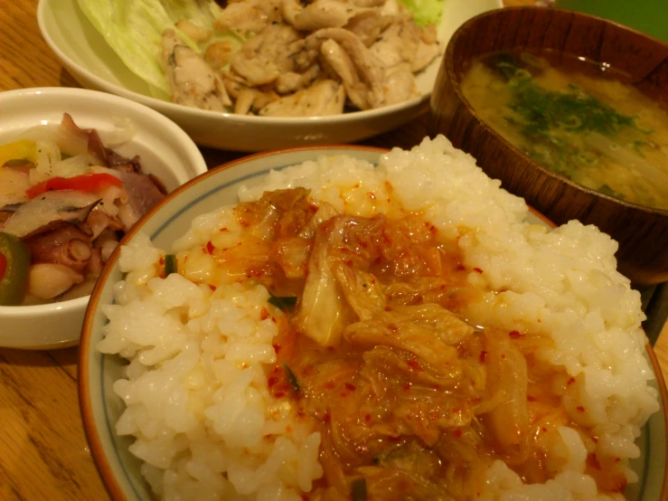 three plates of food, including rice and meat, are sitting on the table