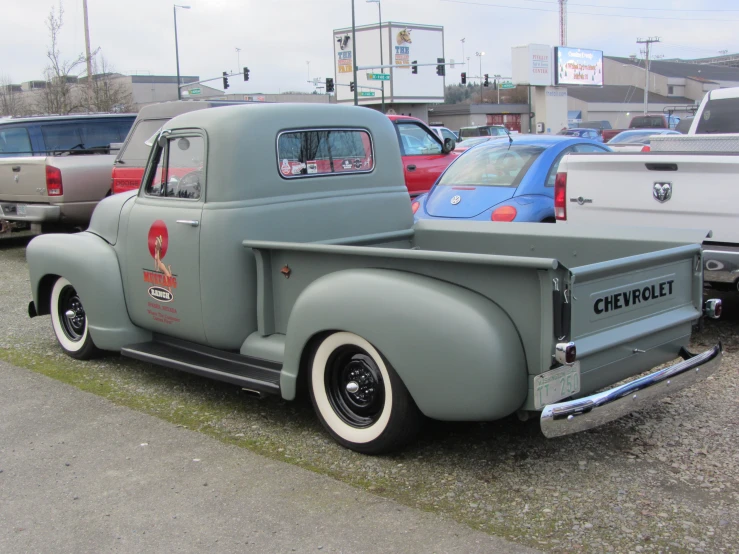 an antique truck is parked in a lot with other cars