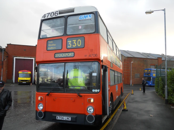 a red two level bus sitting in front of a brick building