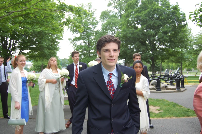 a young man wearing a suit is posing with friends