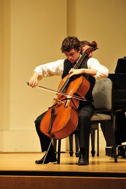 a man in white shirt and tie playing cello