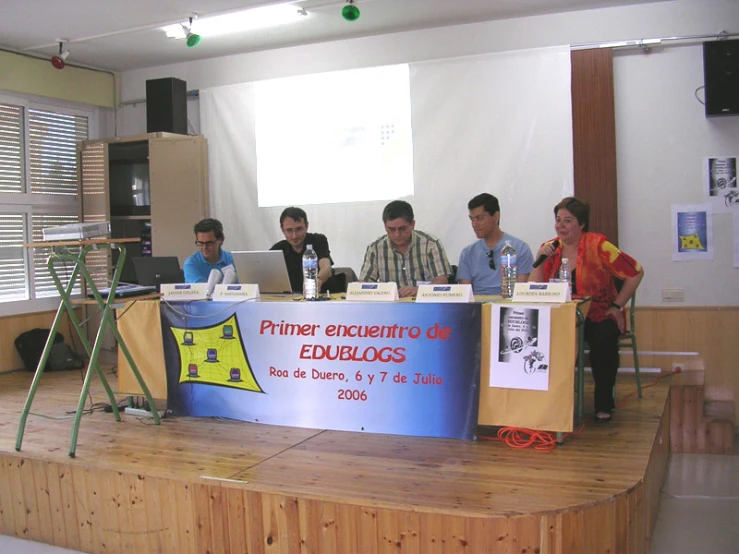 four men are sitting at a table with their laptops