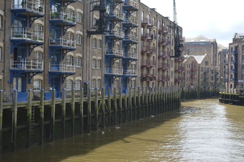 a row of old brown brick apartment buildings on the side of a river
