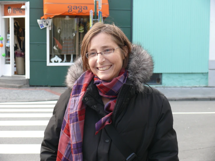 a woman wearing a scarf is standing in front of a green store