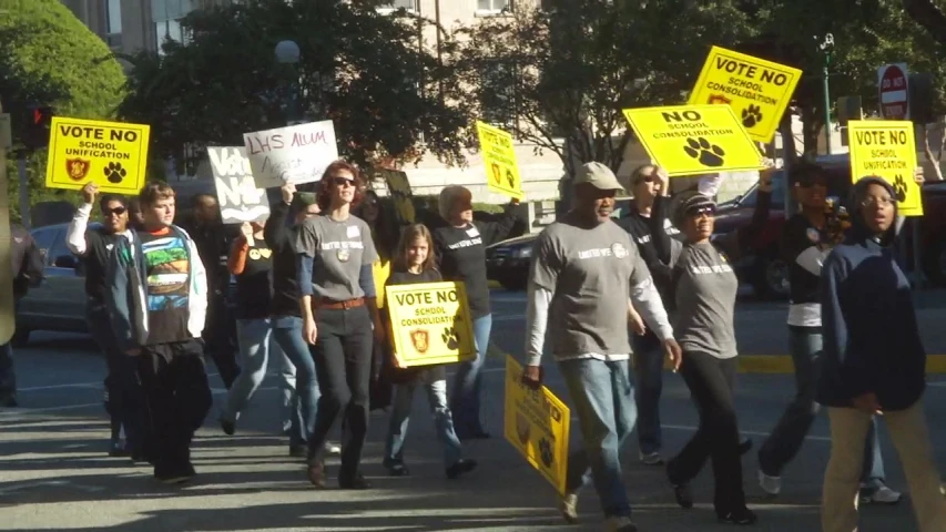 many people marching down a city street with protest signs