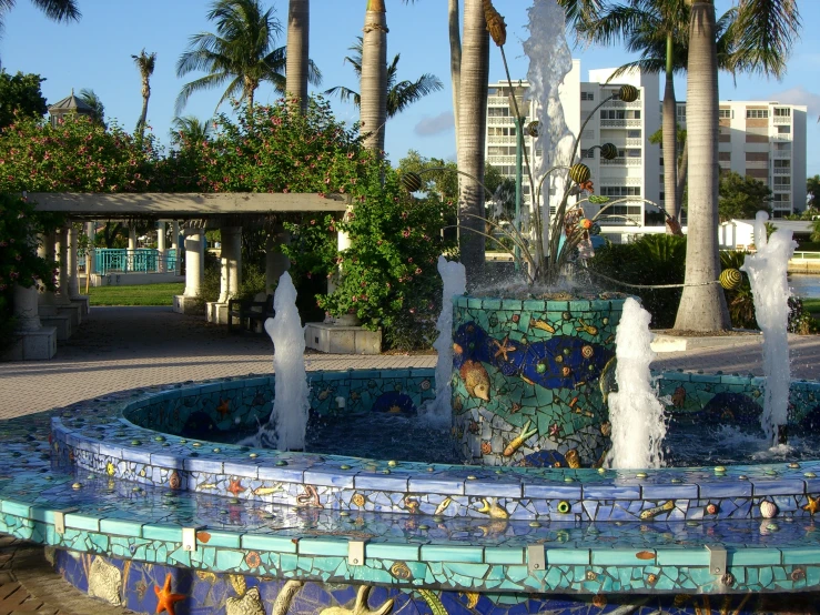 an elaborate fountain near palm trees in front of some els