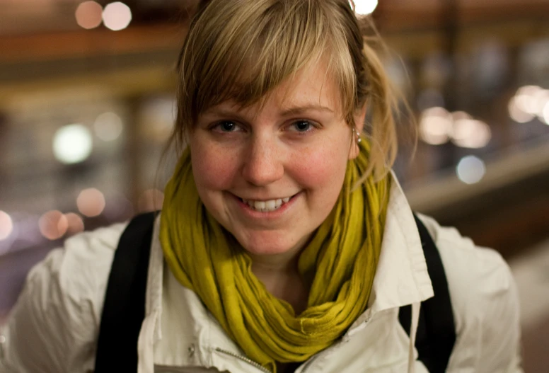 a smiling woman with a yellow scarf around her neck