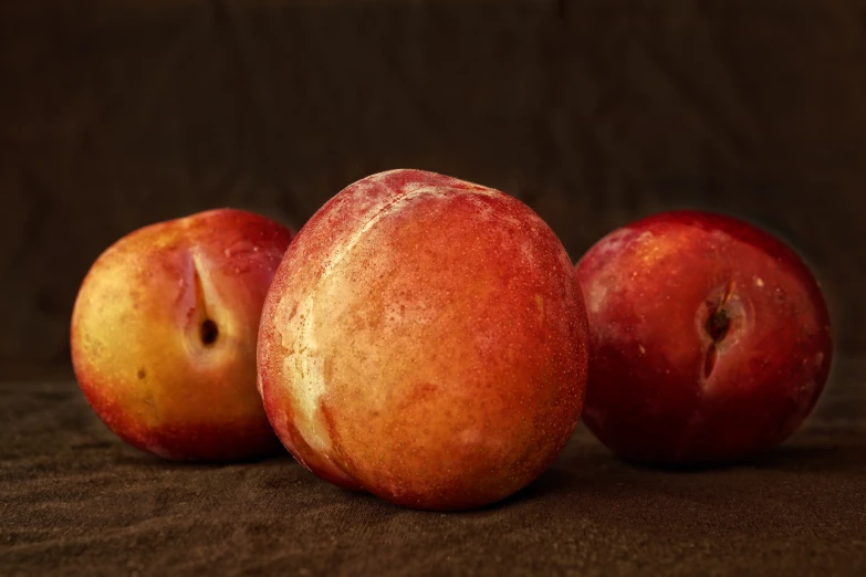 three apples sitting side by side on a brown cloth